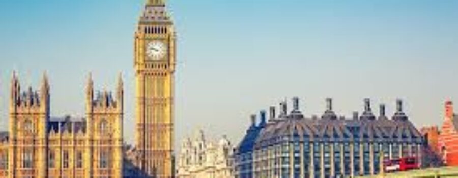 View of the Elizabeth Tower, known as Big Ben, and the Houses of Parliament in London, with a red double-decker bus on Westminster Bridge on a clear day.