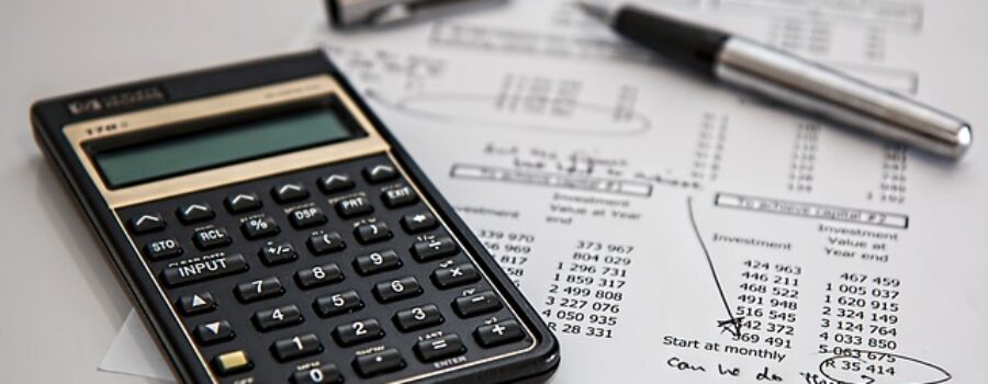 A calculator and pen on financial documents with handwritten notes.
